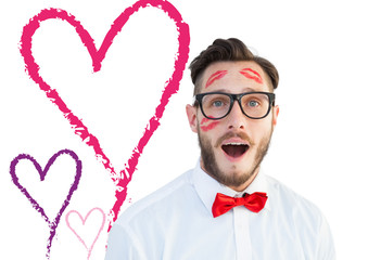 Geeky hipster with kisses on his face against valentines love hearts