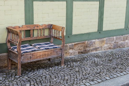 Old small wooden bench on the footpath in front of the house