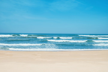 Fototapeta na wymiar Sandy beach and choppy waves. White sand, blue sky and crystal sea of tropical beach