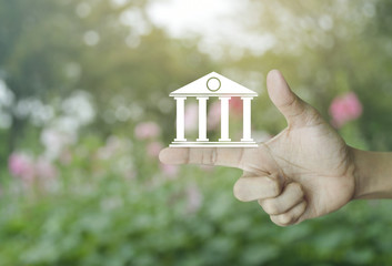 Bank icon on finger over blur pink flower and tree, Business banking online concept