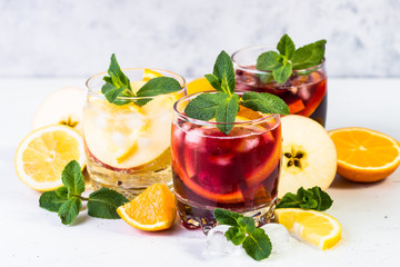 White, pink and red sangria with fruit, ice and mint.