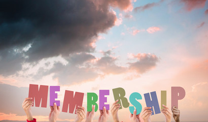 Hands holding up membership against orange and blue sky with clouds