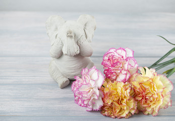 Flowers of various colors next to elephant figure on wooden table. Decor.