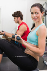 Fototapeta premium Smiling brunette working out on the rowing machine