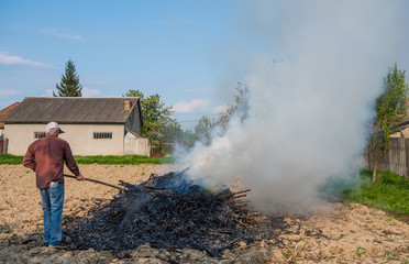 Work in the garden. Farmer burning dried branches