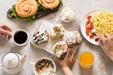Variety of dishes at the family breakfast. Children's, women's and men's hands. Flat lay.