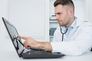 Hardware professional examining laptop with stethoscope