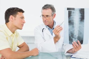 Fototapeta premium Doctor explaining spine xray to patient in office