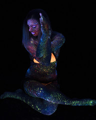 Portrait of Beautiful Fashion Woman Doing Yoga in Neon UF Light. Model Girl with Fluorescent Creative Psychedelic MakeUp, Art Design of Female Disco Dancer Model in UV