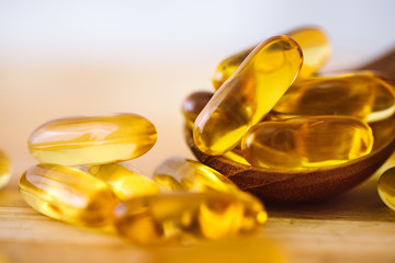 Close up the vitamin D and Omega 3 fish oil capsules supplement on wooden plate for good brain ,...