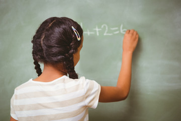 Rear view of little girl writing on blackboard
