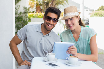 Smiling couple using digital tablet at cafÃƒÂ©