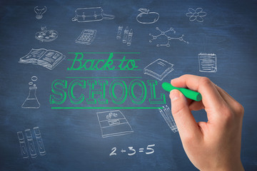 Hand holding blue chalk against blue chalkboard