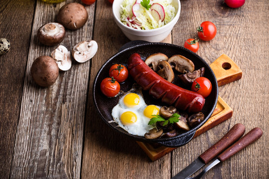 Fried quail eggs, sausage,  tomatoes and mushrooms on cast iron skillet