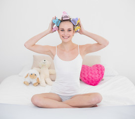 Pretty natural brown haired woman fixing her hair curlers