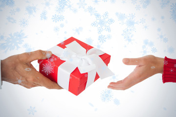 Couple passing a wrapped gift against snow falling