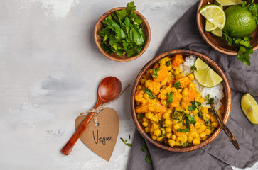 Vegan Sweet Potato Chickpea curry in wooden bowl on a light background, top view. Healthy vegetarian food concept.
