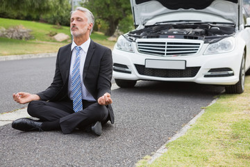 Businessman meditating after his car broken down 