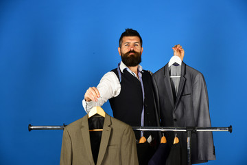 Businessman with proud face holds grey suits on blue background