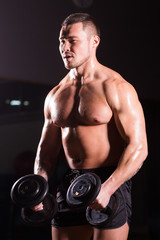 Obraz na płótnie Canvas Handsome power athletic man with dumbbell. Strong bodybuilder with six pack, perfect abs, shoulders, biceps, triceps and chest