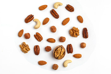 Different kinds of nuts laid out in the shape of a circle, isolated on white background.
