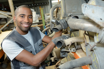 Portrait of worker with used vehicle silencers