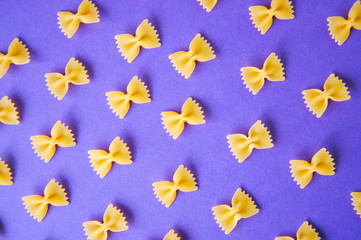 Diagonals of farfalle pasta on a violet background.