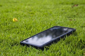 A mobile phone resting on a green grass