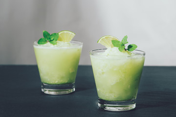 Cocktail juice with lime, mint and ice. Bar drink accessories on black table background.