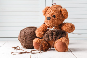 Knitting leisure, ball of wool and needle in hands of toy bear