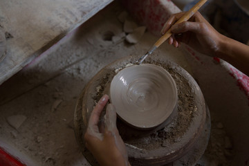 Female potter molding a bowl with hand tool