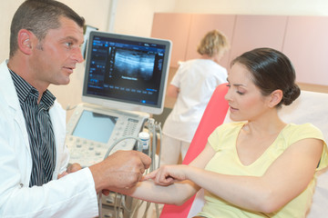 male doctor with female patient undergoing arm echography
