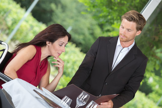 Waiter showing menu to woman in wheelchair