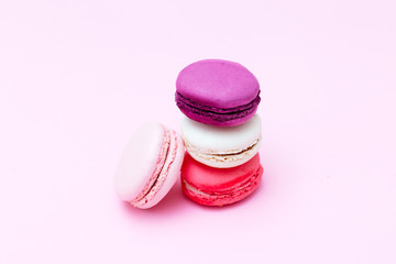 Multicolored macaroons and flowers on pink background.