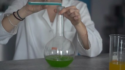 Woman scientist mixing chemicals in flask, slow motion
