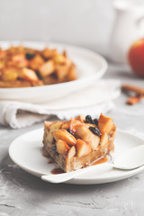 Piece of vegan apple pie with cinnamon, raisins and caramel, gray background.