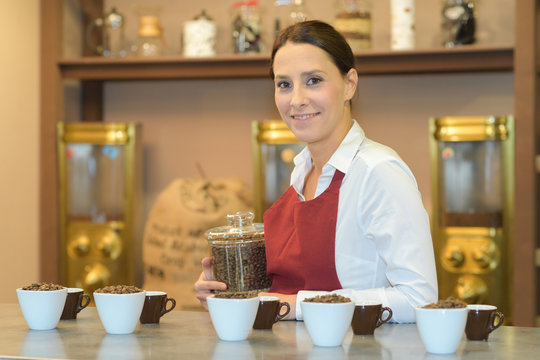 waitress or barista in apron holding coffee