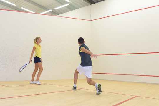 couple play some squash together in the squash court