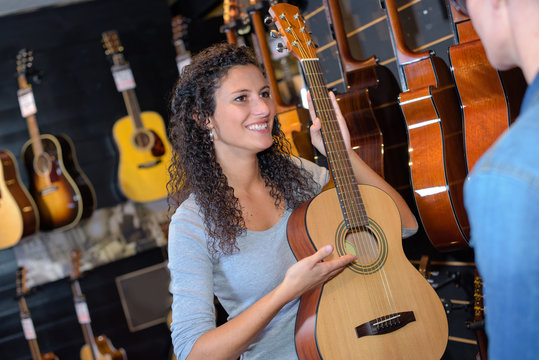 woman holding acoustic guitar at music store