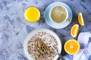 A healthy breakfast of chocolate muesli with coffee, oranges and juice on a gray background. Top view, flat lay, still life