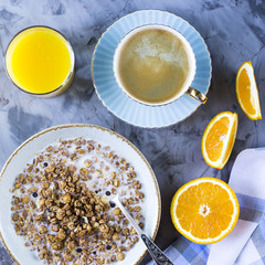 A healthy breakfast of chocolate muesli with coffee, oranges and juice on a gray background. Top view, flat lay, still life