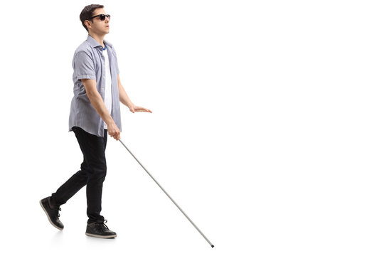 Young blind person with long cane walking in a city Stock Photo by