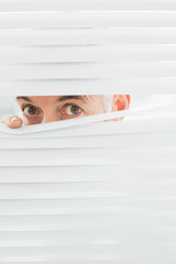 Closeup portrait of a businessman peeking through blinds