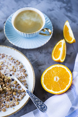 A healthy breakfast of chocolate muesli with coffee, oranges and juice on a gray background. Top view, flat lay, still life