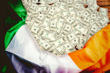 Pile of dollars against irish flag on table