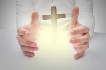 Hands holding against wooden cross