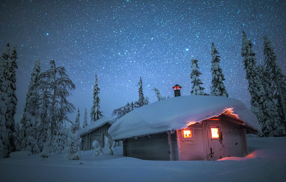 Night sky over snow covered house in forest