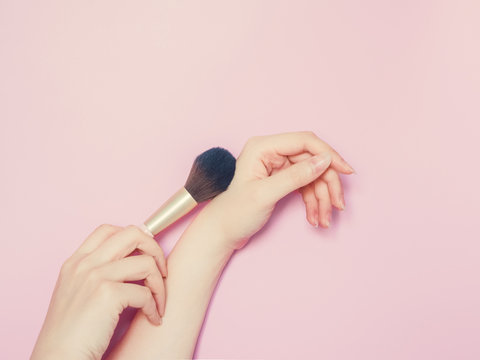 cosmetic and beauty concept from beauty asian hand hold and use cosmetic brush paint on hand with isolated pink pastel background