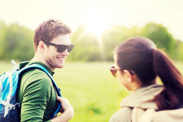 Fototapeta premium travel, hiking, backpacking, tourism and people concept - smiling couple with backpacks in nature looking at each other