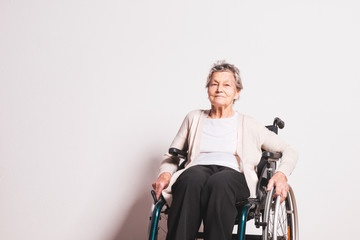 Portrait of a senior woman with wheelchair in studio.